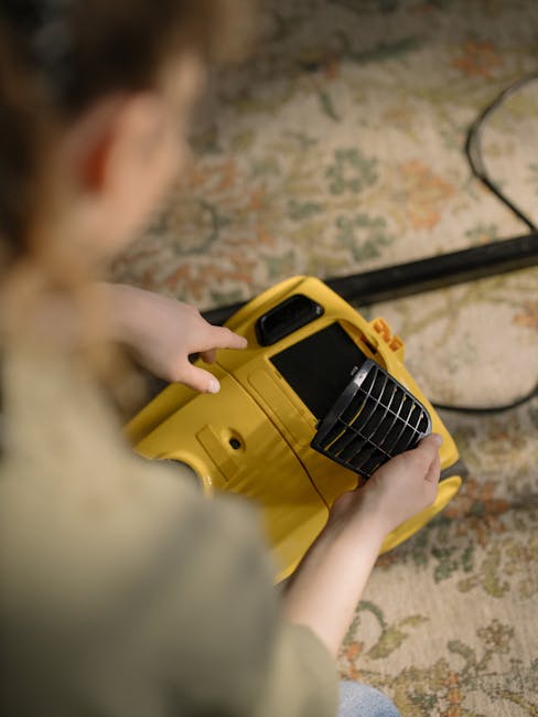 A woman with brown hair tied back, dressed in a light-colored, striped shirt and blue jeans, is kneeling on a patterned rug while wiping the wooden floor with a blue cloth. The room features a neatly