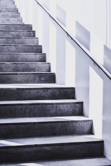 Close-up image of a wooden staircase in a residential flat, showcasing the polished wooden steps with a slight shine, indicating recent cleaning or maintenance. The staircase is situated within a narr